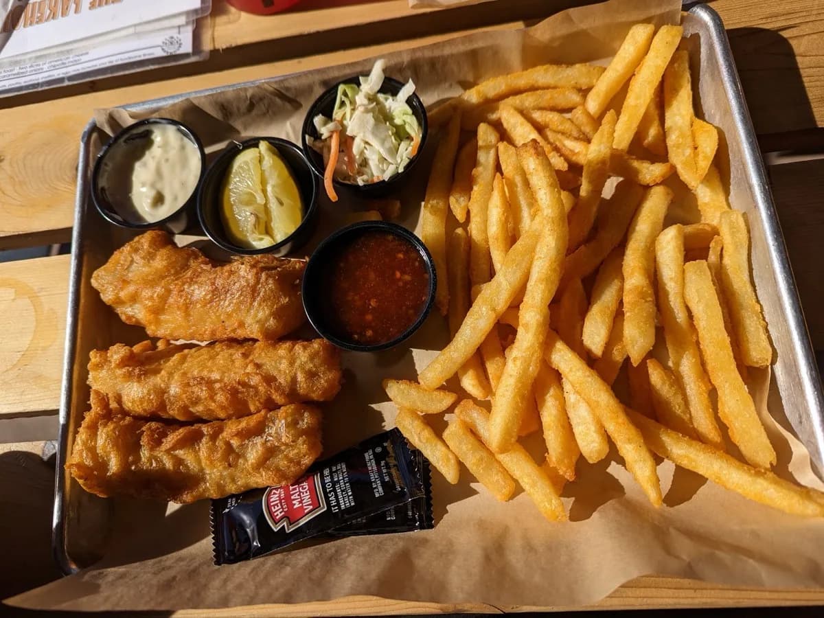 The Lakehouse fish and chips — three battered cod fillets, coleslaw, pickle, cocktail sauce, tartar sauce, and french fries on a tray